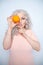 Charming plump curly blonde in pink dress with orange on white solid studio background alone