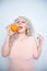 Charming plump curly blonde in pink dress with orange on white solid studio background alone