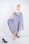 Charming plus size young woman in grey gown dress lost slipper on white background in Studio. beautiful chubby short hair blonde g