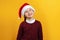 Charming Portrait of a happy cute little girl in a Santa hat. The child is dreamily looking up on a yellow background