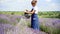 Charming positive gardener watering lavender on sunny summer field. Wide shot of joyful happy Caucasian woman taking