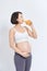 Charming pregnant woman holding a glass of orange juice while standing