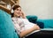 Charming pregnant young redhead Caucasian woman resting on maternity leave, gently stroking her pregnant tummy and enjoying