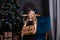 charming preschool blonde girl in a black dress standing near a christmas tree with blue decorations in dark room