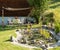 Charming relaxation area in a garden, at the edge of a Zen ornamental pool, surrounded by metal bird sculptures. Pond decorated