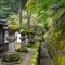 Charming scene of japanese stone lanterns with green moss with fresh green trees, background