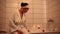 Charming serene African woman in a white waffle robe sits on the edge of the tub and fills up with water for a relaxing bubble bat