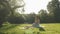 Charming serene lady in hat sitting on meadow near river, relaxing and enjoying summer vacation. Woman in dress relaxing in park.