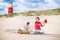 Charming siblings on the beach next to lighthouse