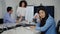 Charming slim Asian businesswoman sitting at conference table shaking head as blurred colleagues arguing at background