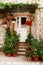 Charming small home with white front door and summer garden containers filled with annual flowers