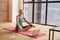 Charming sportive mature woman sitting in Lotus pose on the floor and smiling while meditating and practicing yoga at