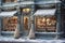 A charming storefront with frost-covered windows, showcasing a variety of beautifully arranged Christmas decorations, enticing