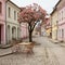 Charming street with tables, chairs, and trees in pastel colors