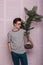 Charming stylish young man fashion model in a fashionable striped T-shirt in jeans with glasses with an amazing exotic plant in a