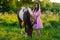 Charming teenager girl in pink dress with horse in the field