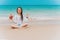 Charming teenager girl in a white shirt and with long hair meditates in a lotus position on the seashore. In the hands of a dragon