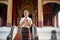 A charming Thai lady in a traditional dress with a garland in her hands is in a beautiful temple