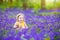 Charming toddler girl in bluebell flowers in spring forest