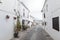 Charming white narrow streetwith restaurants with souvenir shops with beautiful flowers on the walls. Mijas
