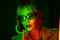 Charming woman with dyed green hair posing under neon light. Unusual mysterious lady in sunglasses, nightlife concept