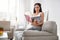 Charming woman reading magazine while kneeling on sofa