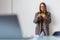 Charming woman with a smile standing holding mobile phone at the office