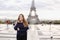 Charming woman standing in Eiffel Tower background in Paris.