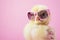 A charming yellow chick wearing oversized pink sunglasses, with a pink background.