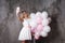 Charming young blonde in a white dress with pink balloons, make a selfie.