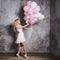 Charming young blonde in a white dress with pink balloons, at the party.