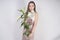 A charming young caucasian girl stands in a delicate pale short prom dress with flowers application and poses on a white backgroun