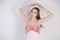 A charming young caucasian girl stands in a pink long prom dress with flower petals on her chest and poses on a white background i