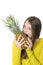 Charming young girl bites a large ripe pineapple.