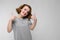 Charming young girl in a gray T-shirt on a gray background. Girl showing class sign