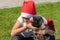 Charming young girl in santa claus hat hugs a dog in santa claus hat in the park on a sunny summer day. The dog licks the tongue
