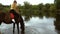 Charming young girl sits astride a horse that drinks water