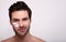 A charming young man with dark hair and a beard, applies face cream