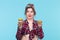 Charming young pin-up girl holding two donuts in her hands and one posing on a blue background. Concept benefits and