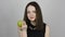 Charming young woman eats a green apple and smiles