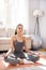 Charming young woman practicing yoga at home