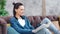 Charming young woman smiling and reading interesting book sitting on couch medium long shot