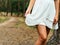 Charming young woman in white dress standing in forest