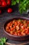 Chashushuli, thick beef stew in tomato sauce with sweet pepper, onion and spices in a clay bowl on a dark wooden background. Beef