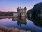Chateau de la Roche castle Castle in Saint-Priest-la-Roche, France reflected in water at sunset