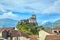 Chateau Fort of Lourdes. Castle on a rock. Snowy mountain peaks. Blue sky with white clouds. Town in the Hautes-PyrÃ©nÃ©es, France