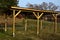 Cheap wooden pergola in the meadow serves as a shelter for the playground in the housing estate. flat roof, yellow wooden columns