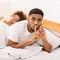 Cheating african husband talking privately on cellphone in family bed