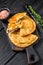 Cheburek meat pastry pie with herbs. Black wooden background. Top view