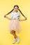 Check out my style. Kid girl charming ponytail hairstyle cute happy yellow background. Child fashionable outfit skirt